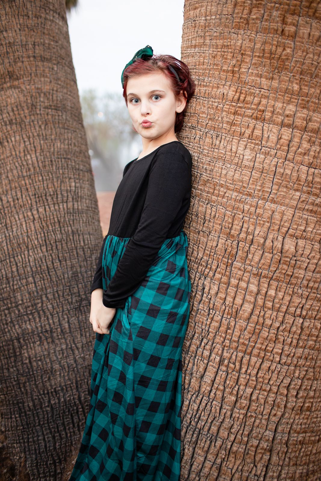 Portrait series showing a person in a teal plaid dress and black top posing against a palm tree trunk background in Papago Park in Phoenix,