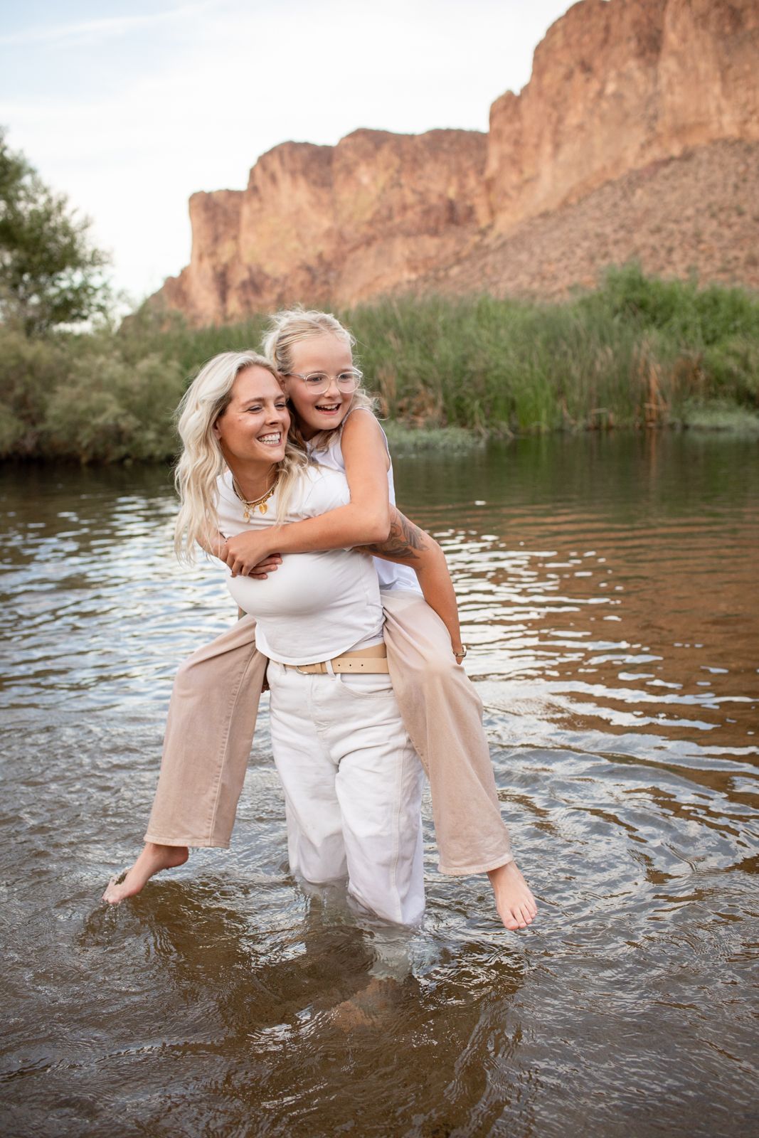 Two people share a joyful moment playing in the water against a backdrop of desert cliffs at Water Users recreational area.