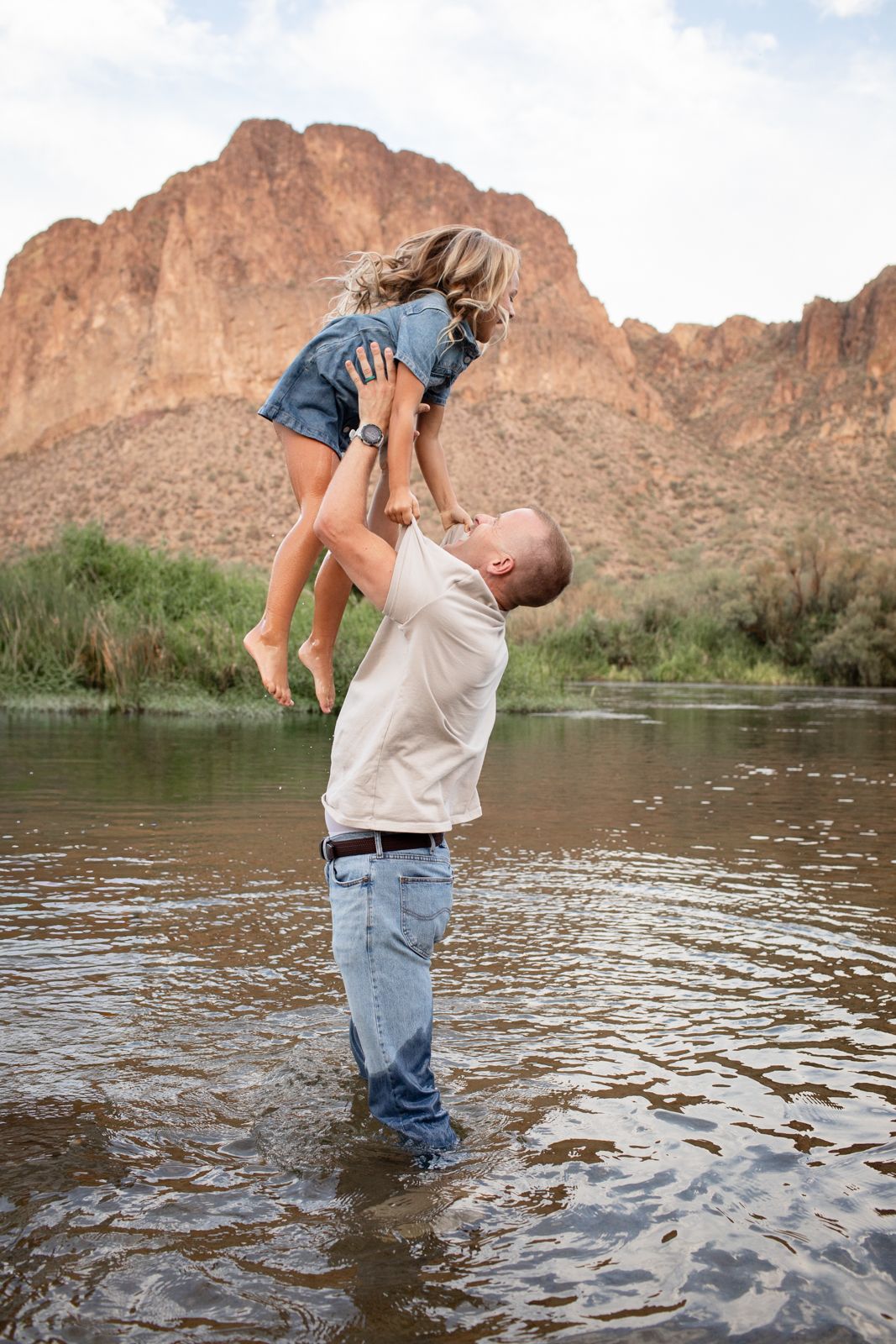 Two people playing in shallow water near  desert mountains during sunset, creating playful splashes at Water Users recreational area.