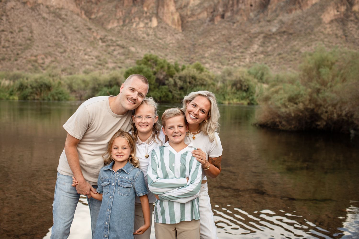 Al Carraway and family portraits by a serene river with natural lighting and reflections on the water.
