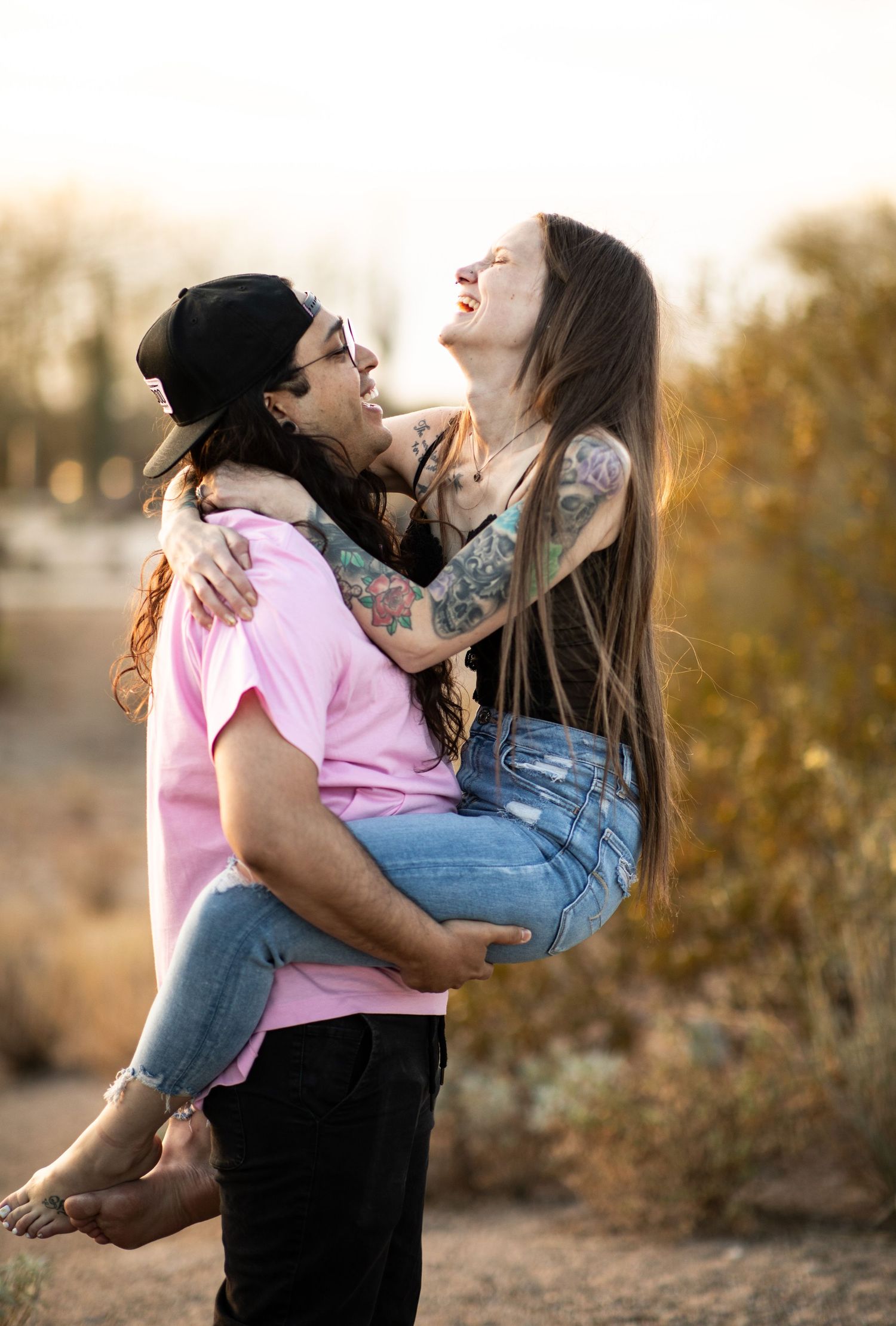 A romantic couple shares playful moments in a desert setting during sunset at Desert Arroyo Park in Mesa, Arizona.