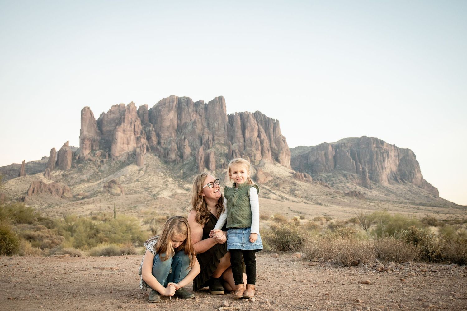 People posing together in front of scenic desert mountains and rock formations at sunset at Lost Dutchman State park.
