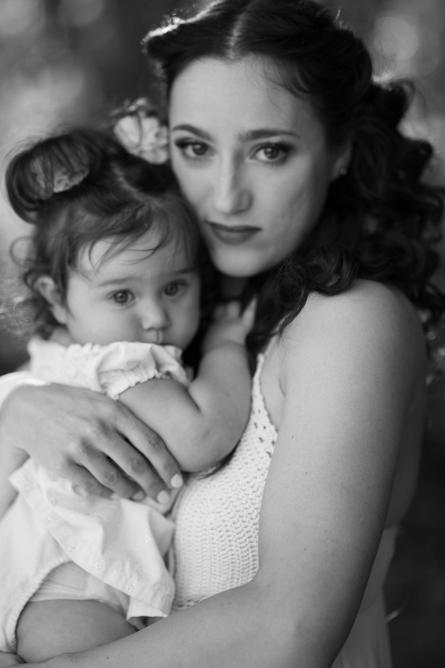 Black and white intimate portrait of mother and child in tender embrace wearing white clothing at The Meadow in Mesa.