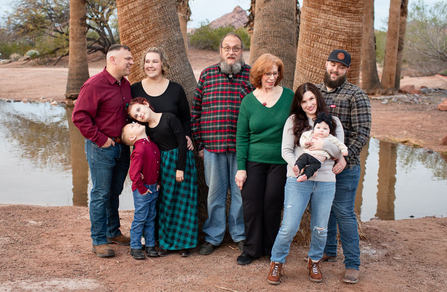 A series of casual outdoor family portraits taken in a rustic desert setting with palm trees and natural lighting in Papago Park in Phoenix