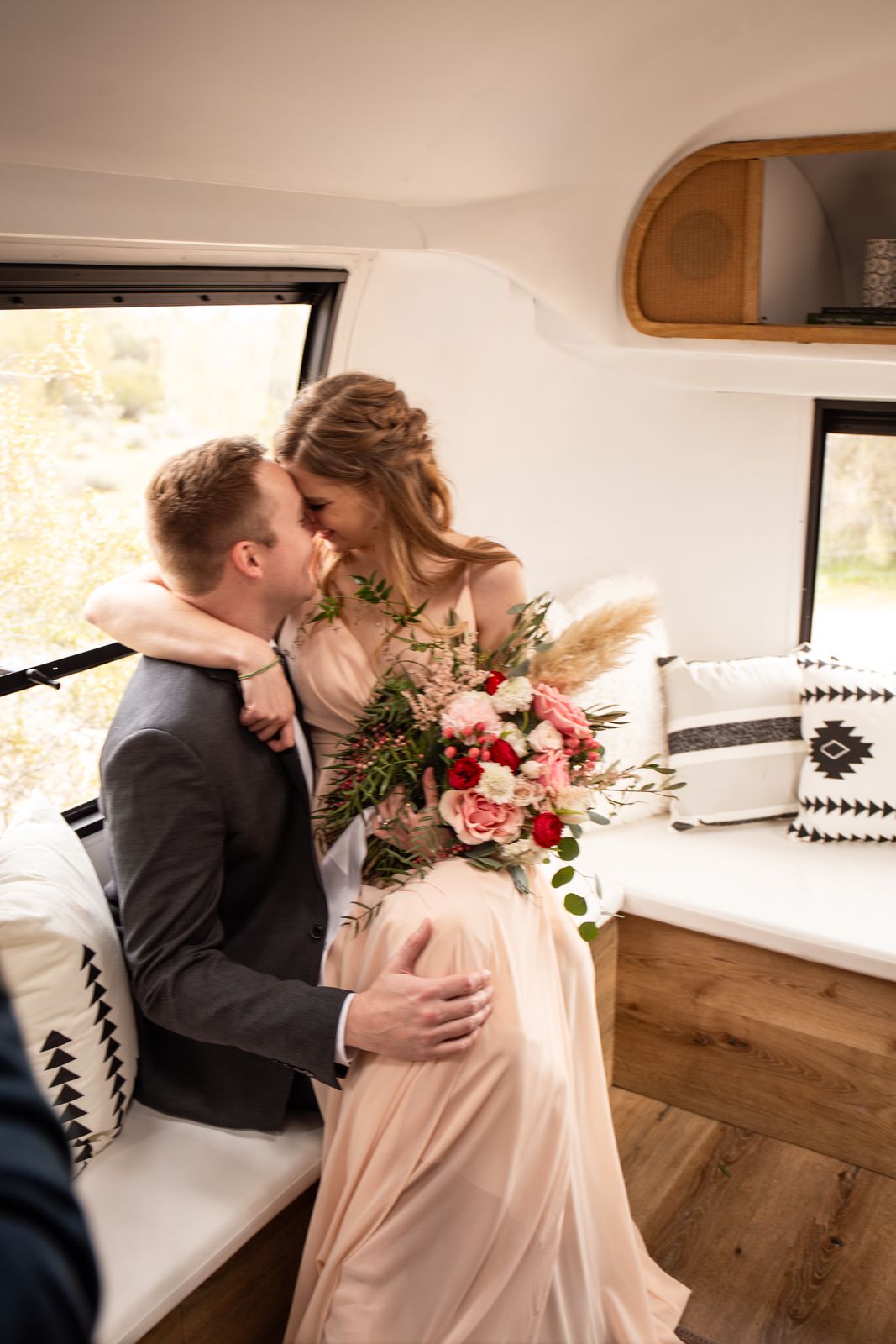 A couple shares a romantic moment in a cozy modern room with white walls and rustic wood accents inside the airstream photobooth.