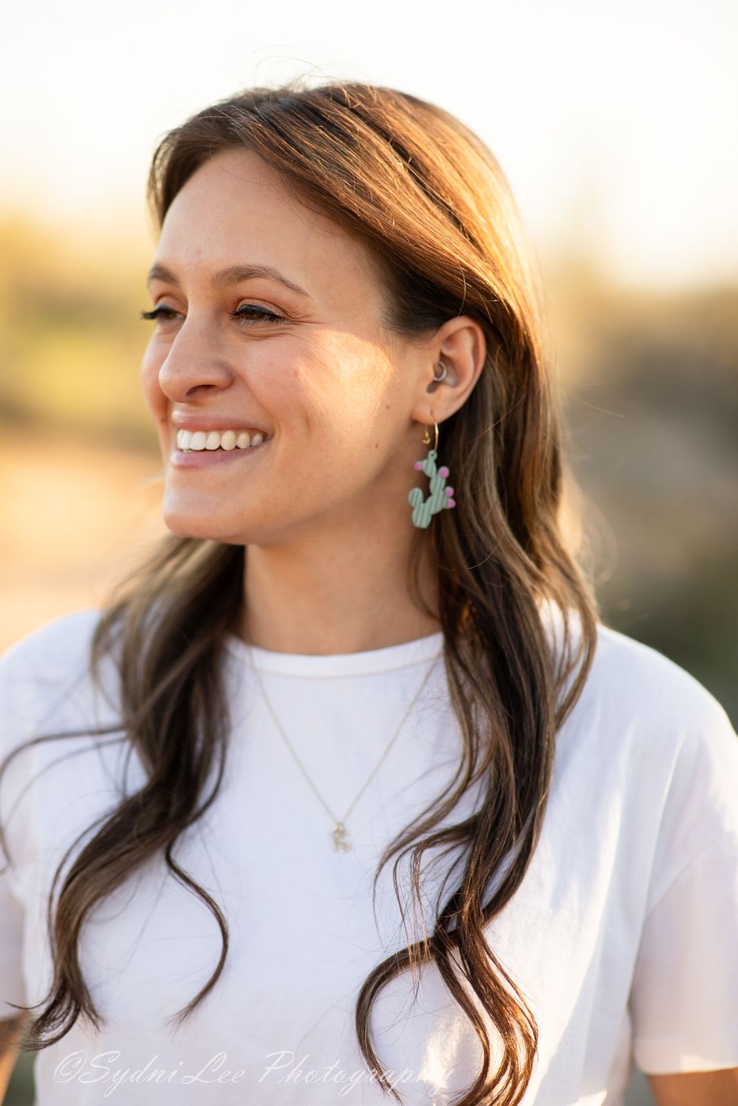 Turquoise earrings complement a classic white t-shirt in warm sunset lighting.