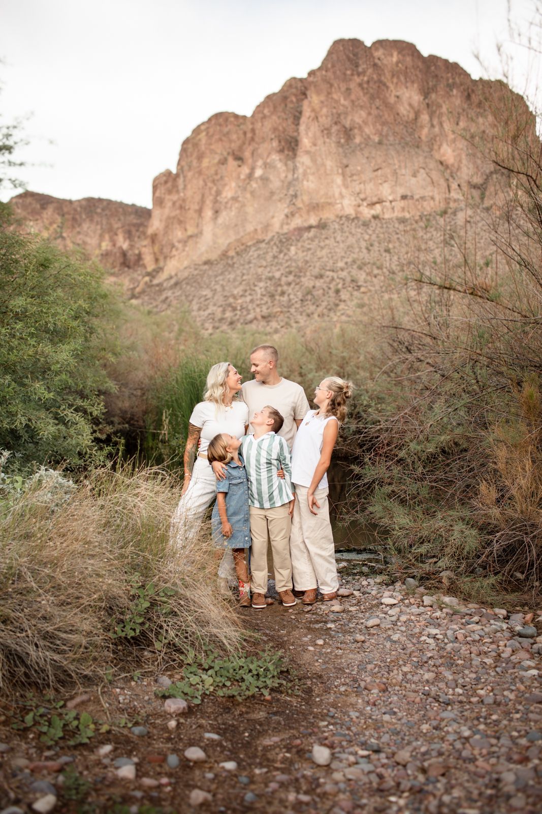 Family group walks along rocky desert trail with rugged mountain landscape in background at Water Users recreational area.