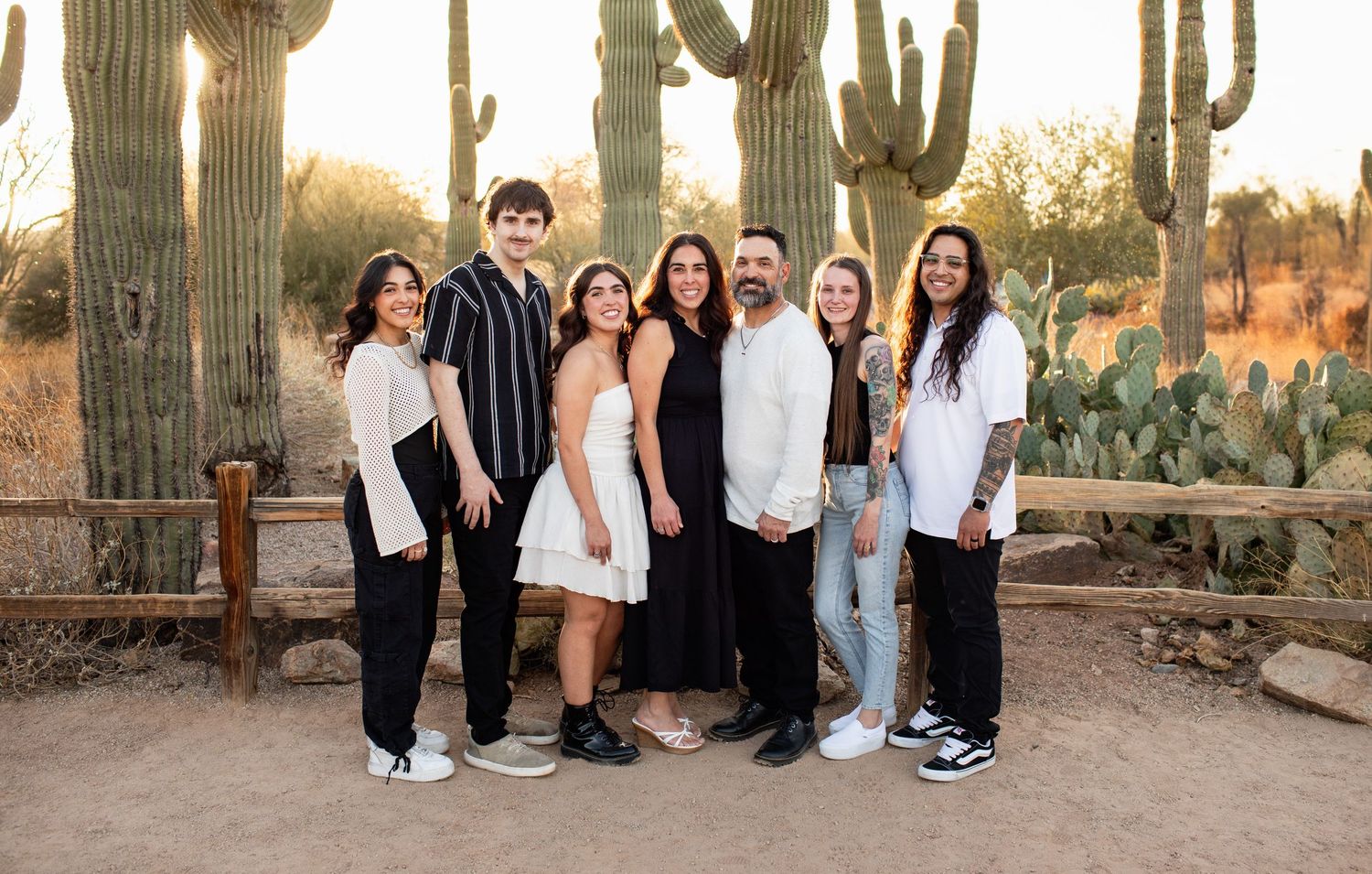 A panoramic collage of people posing in a desert landscape with tall saguaro cacti at sunset.