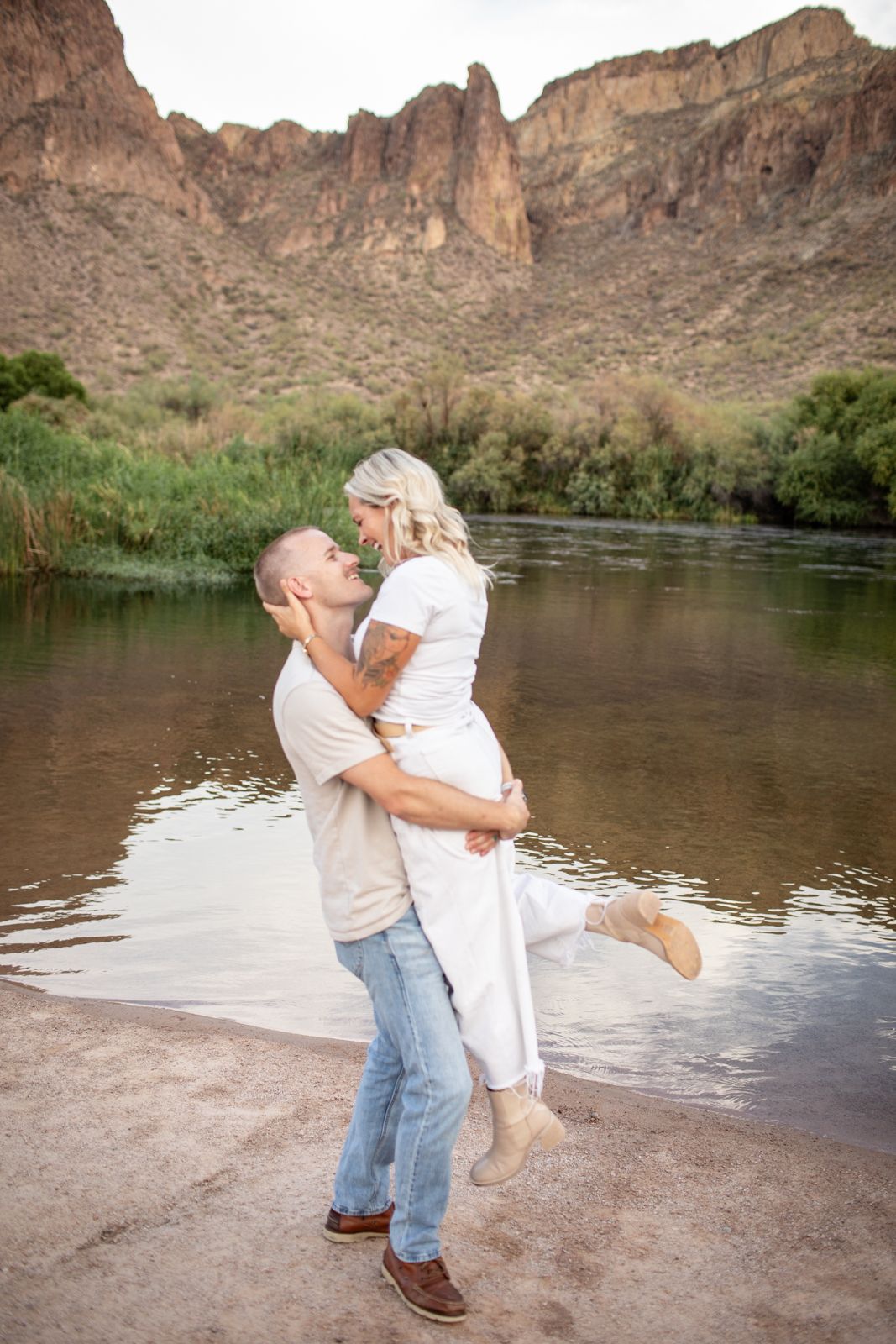 Romantic moment captured by the water as couple spins in celebration against desert mountain landscape at Water Users recreational area.