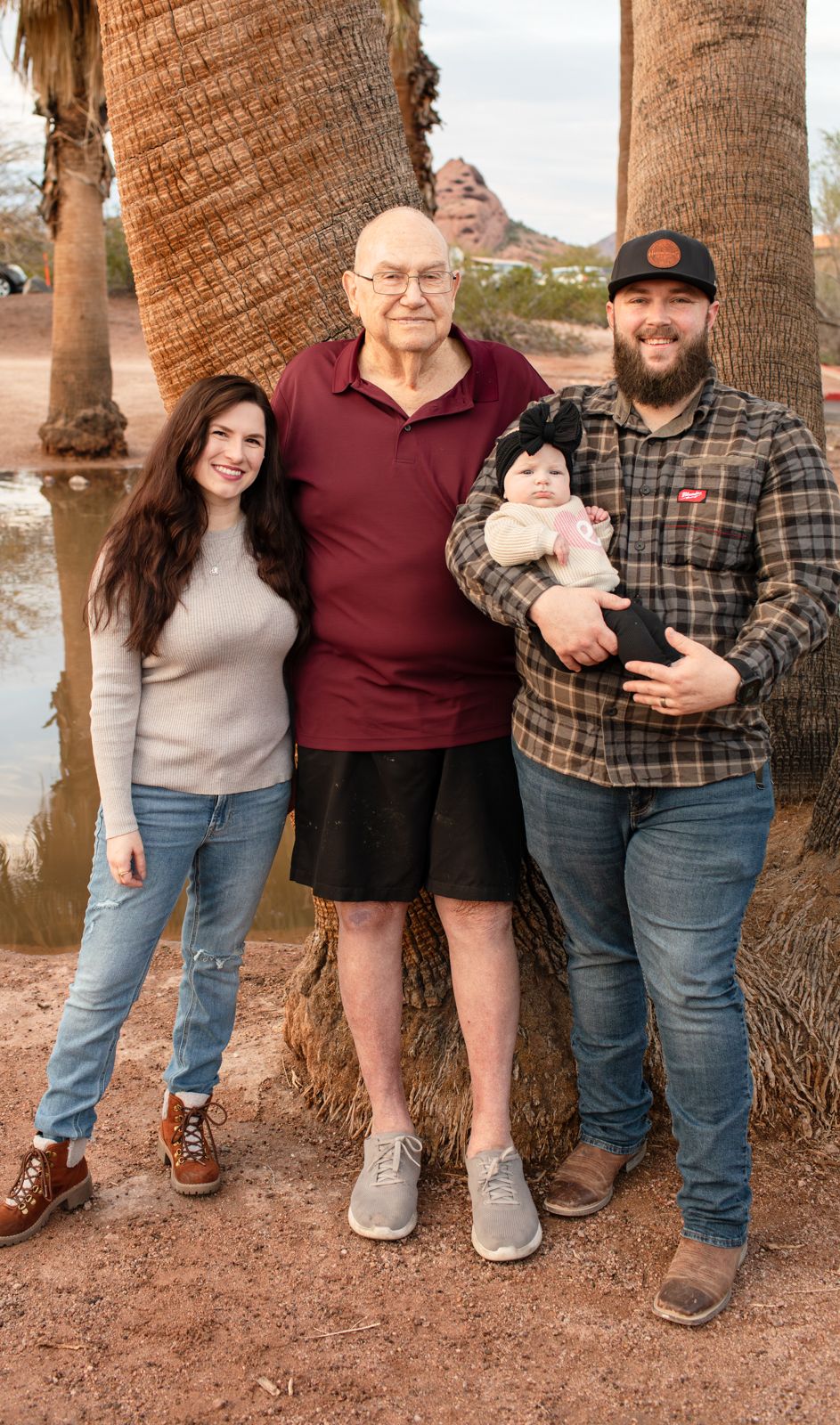 A group of people standing together outdoors near palm trees on a dirt path in Papago Park in Phoenix, AZ.