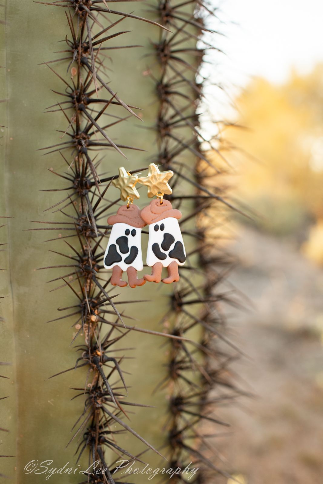 Close-up progression of two small decorative mice figures being placed among desert cactus spines.