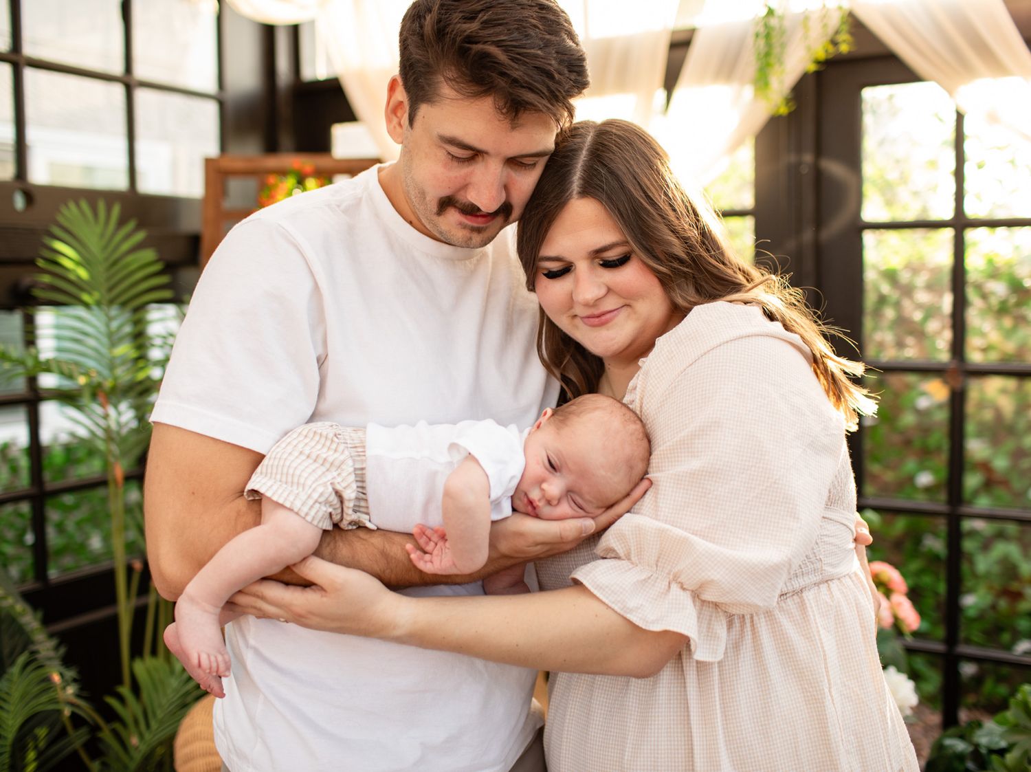 Lifestyle family photography session in a bright greenhouse with flowing white curtains at The Moody Greenhouse in Mesa, Arizona.