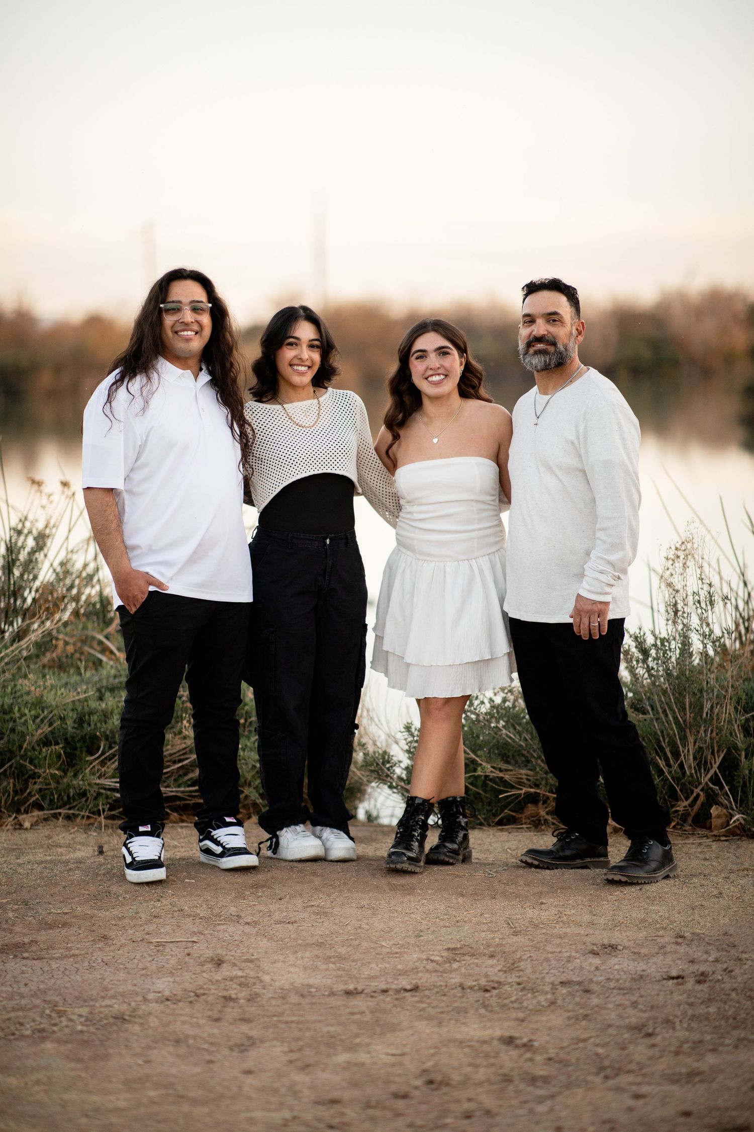 A creative family photo showing only their legs and feet lined up against a natural outdoor backdrop at sunset.