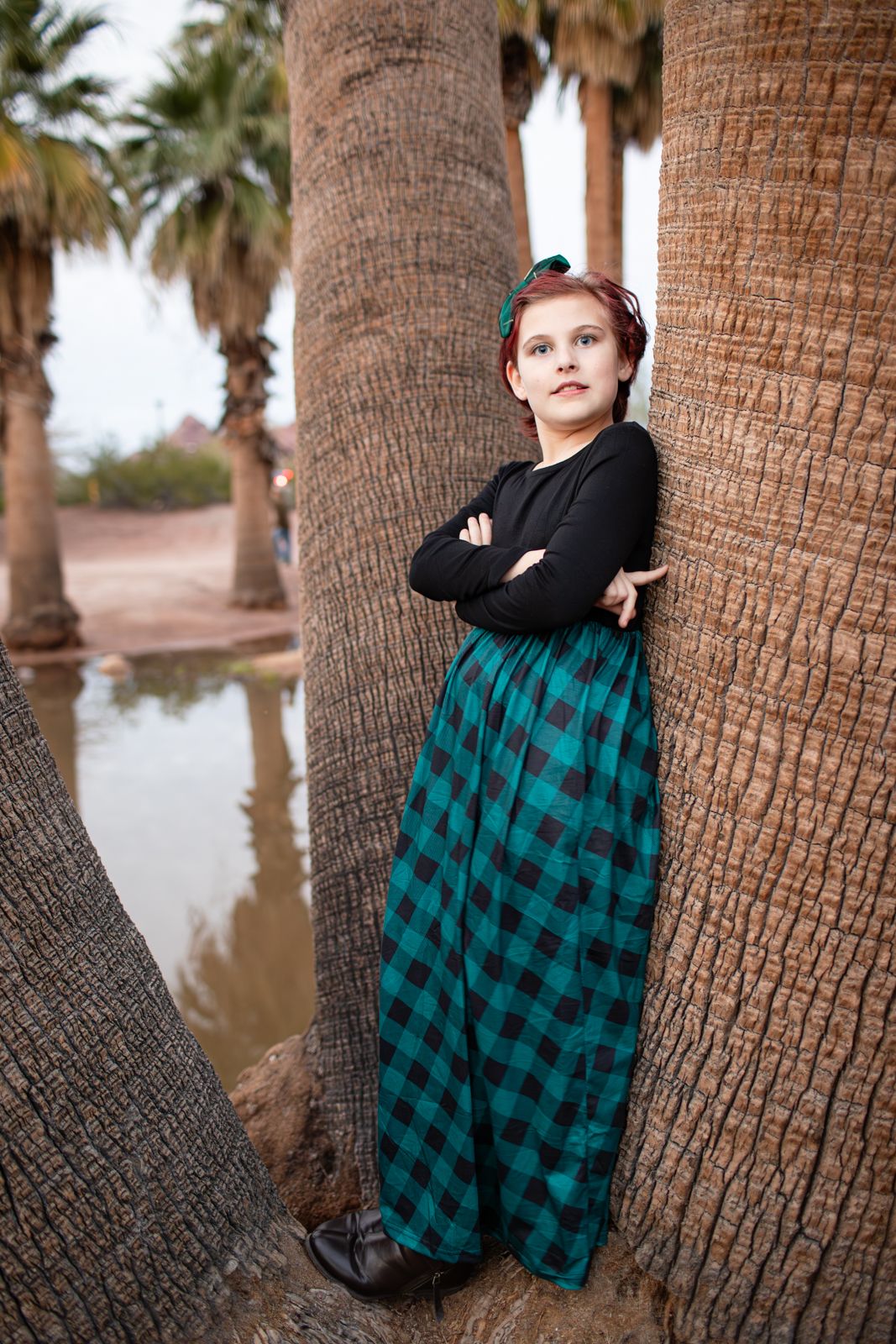 A sequence of photos showing a person in a black sweater and plaid skirt posing against a palm tree trunk in Papago Park in Phoenix, AZ.
