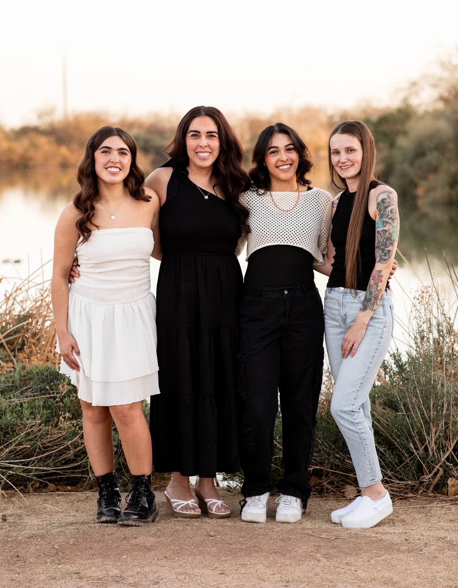 A group poses together in casual outfits against a desert landscape during golden hour sunset.