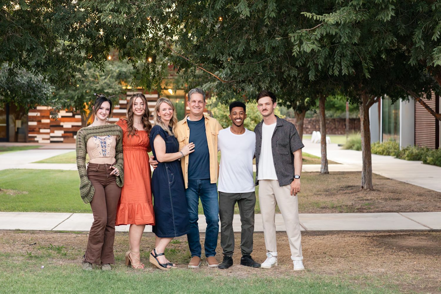 A group poses together outdoors on a sunny autumn day wearing coordinated orange and navy outfits at The Grove Church in Chandler, Arizona.