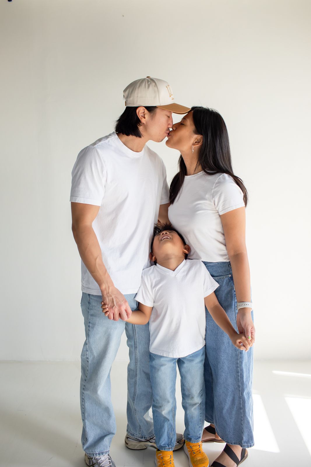 Family in matching casual outfits sharing tender moments against white backdrop at Letty Lume studio in Gilbert, Arizona.