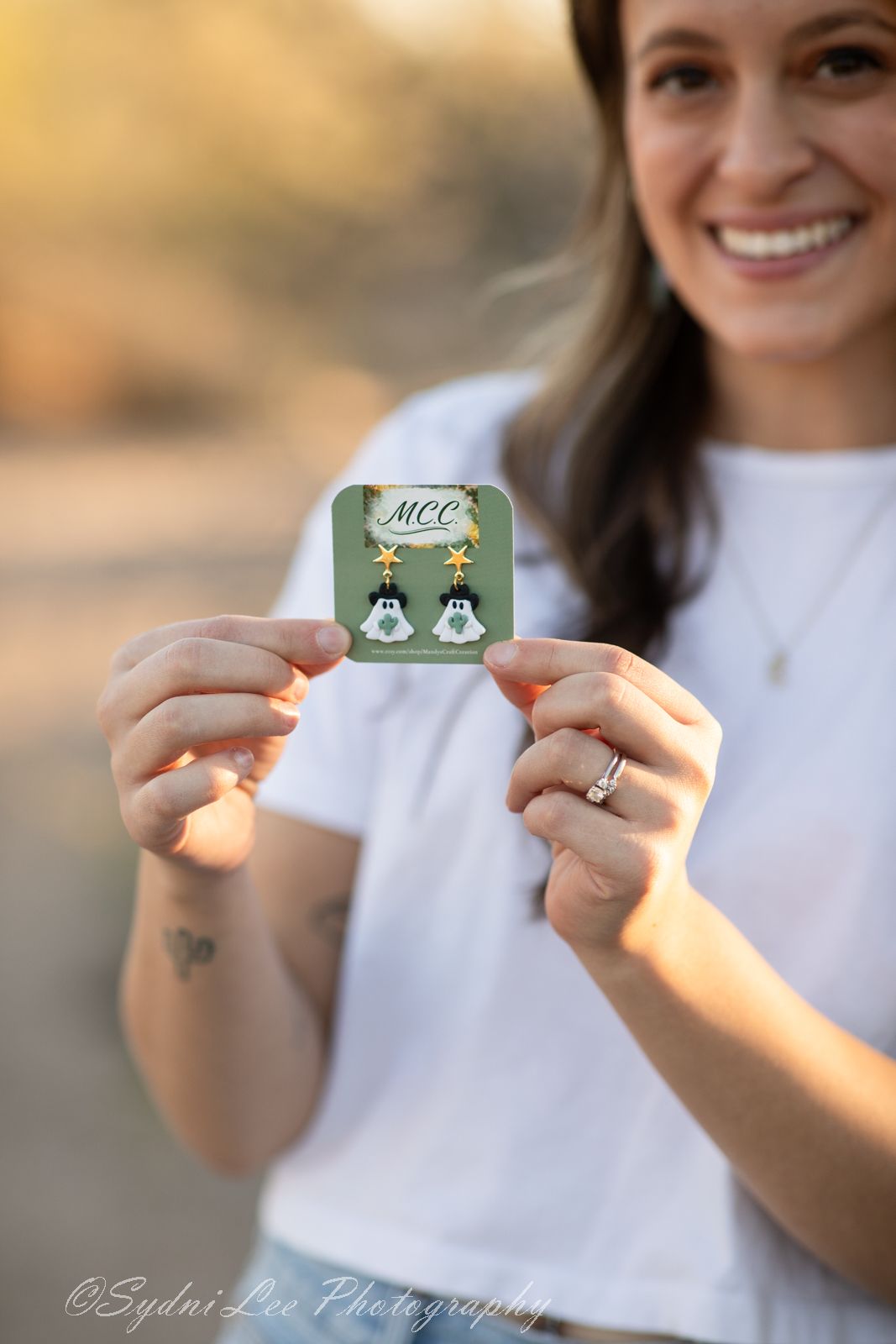 Close-up shots of hands holding small decorative cards against blurred desert background.