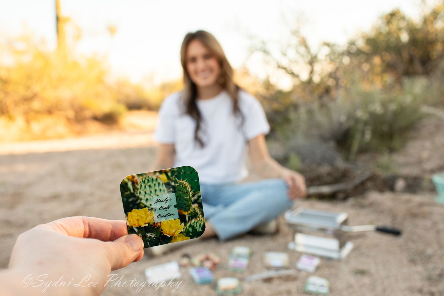 A collection of playing cards and a game box are displayed on a desert landscape during golden hour.