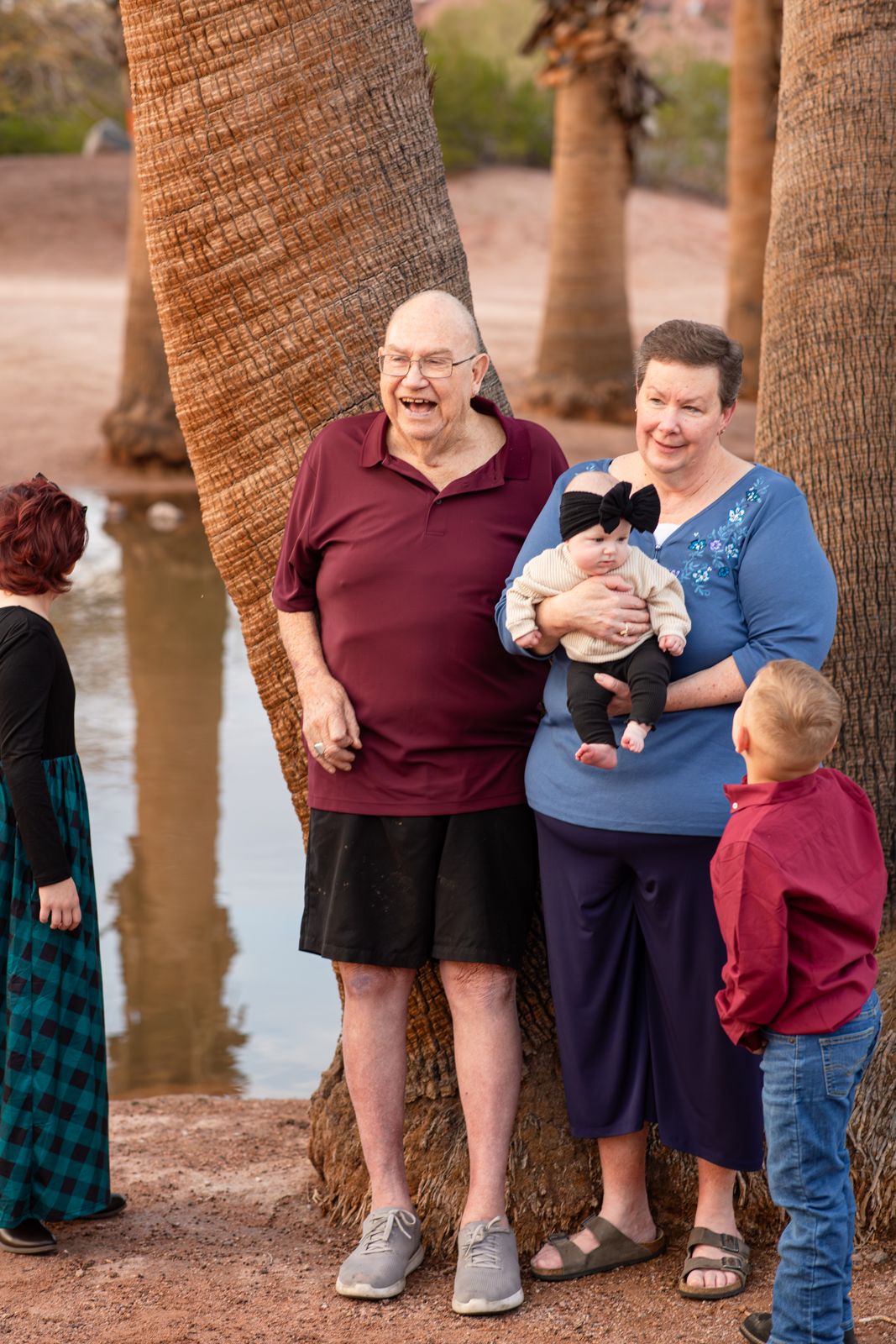 A series of candid outdoor family photos taken near palm trees by a waterfront showing playful interactions in Papago Park in Phoenix, AZ.
