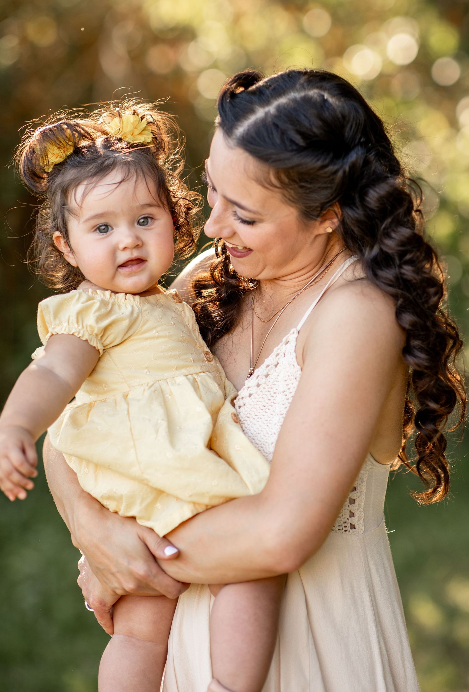 Sweet candid moments between parent and child wearing cream-colored outfits against a dreamy bokeh garden background at The Meadow in Mesa