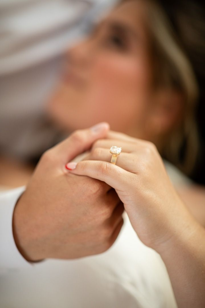 Close-up of hands with wedding rings in soft natural light.