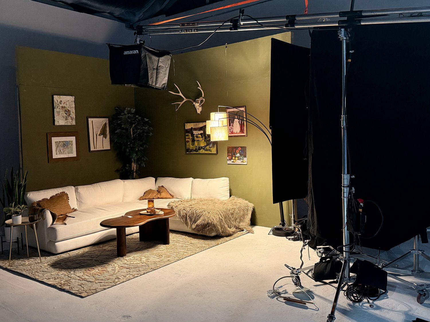 Modern living room setup with dark walls, ambient lighting, and comfortable seating arrangements viewed from multiple angles.