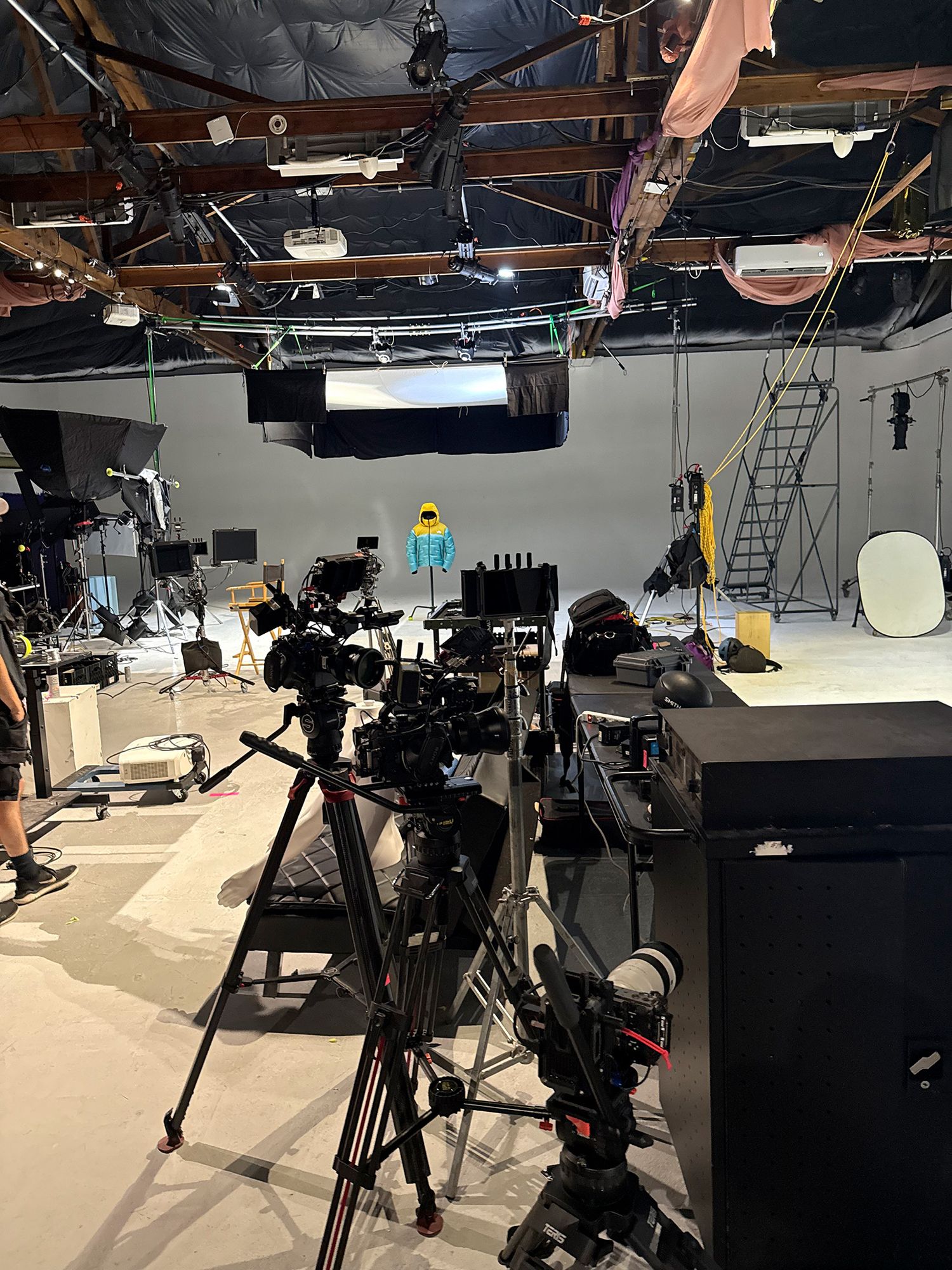 Professional video production equipment setup with multiple tripod-mounted cameras in a dark studio environment.