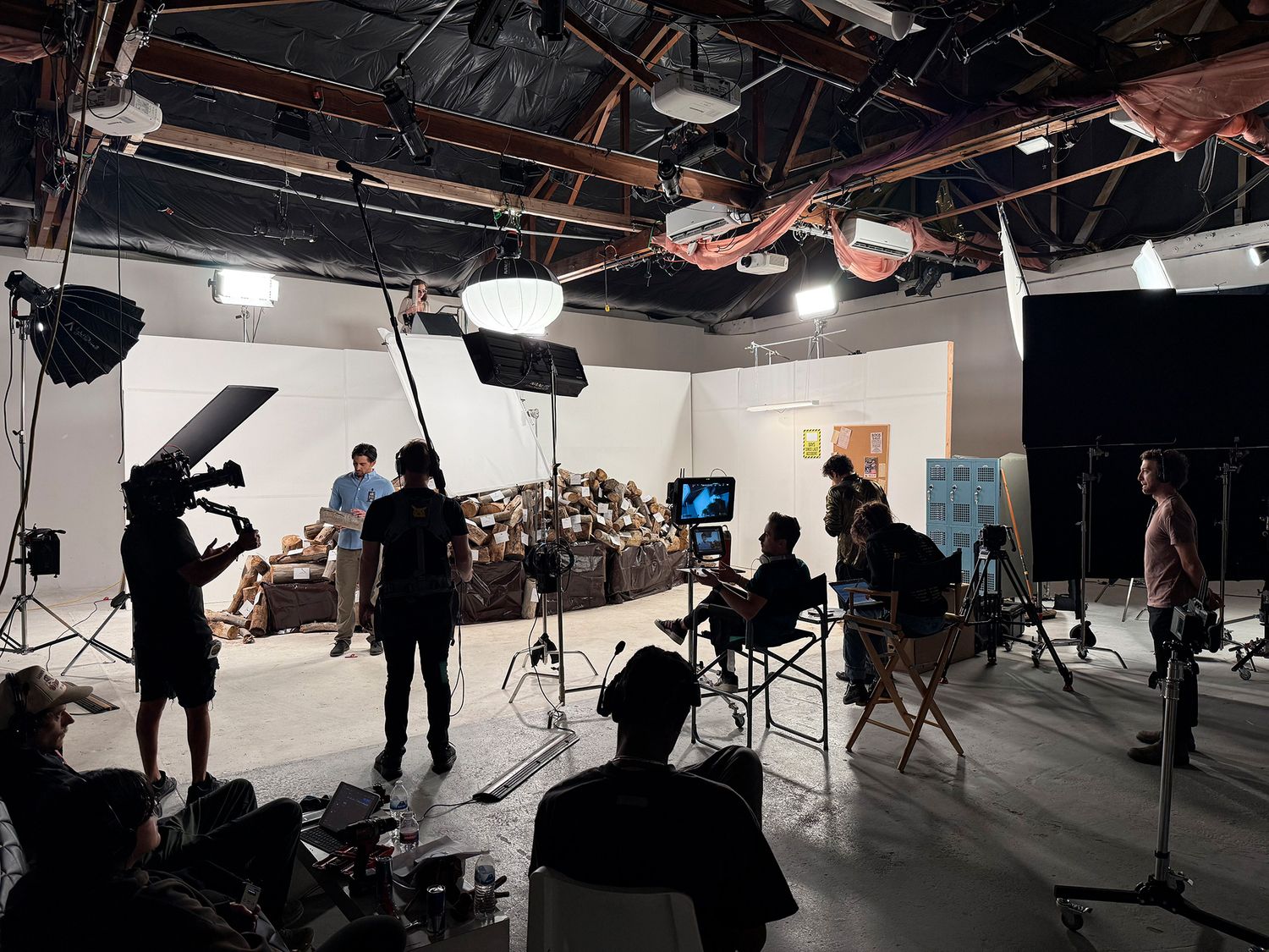 Film crew and production team working on set in a professional video studio with lighting equipment and cameras.