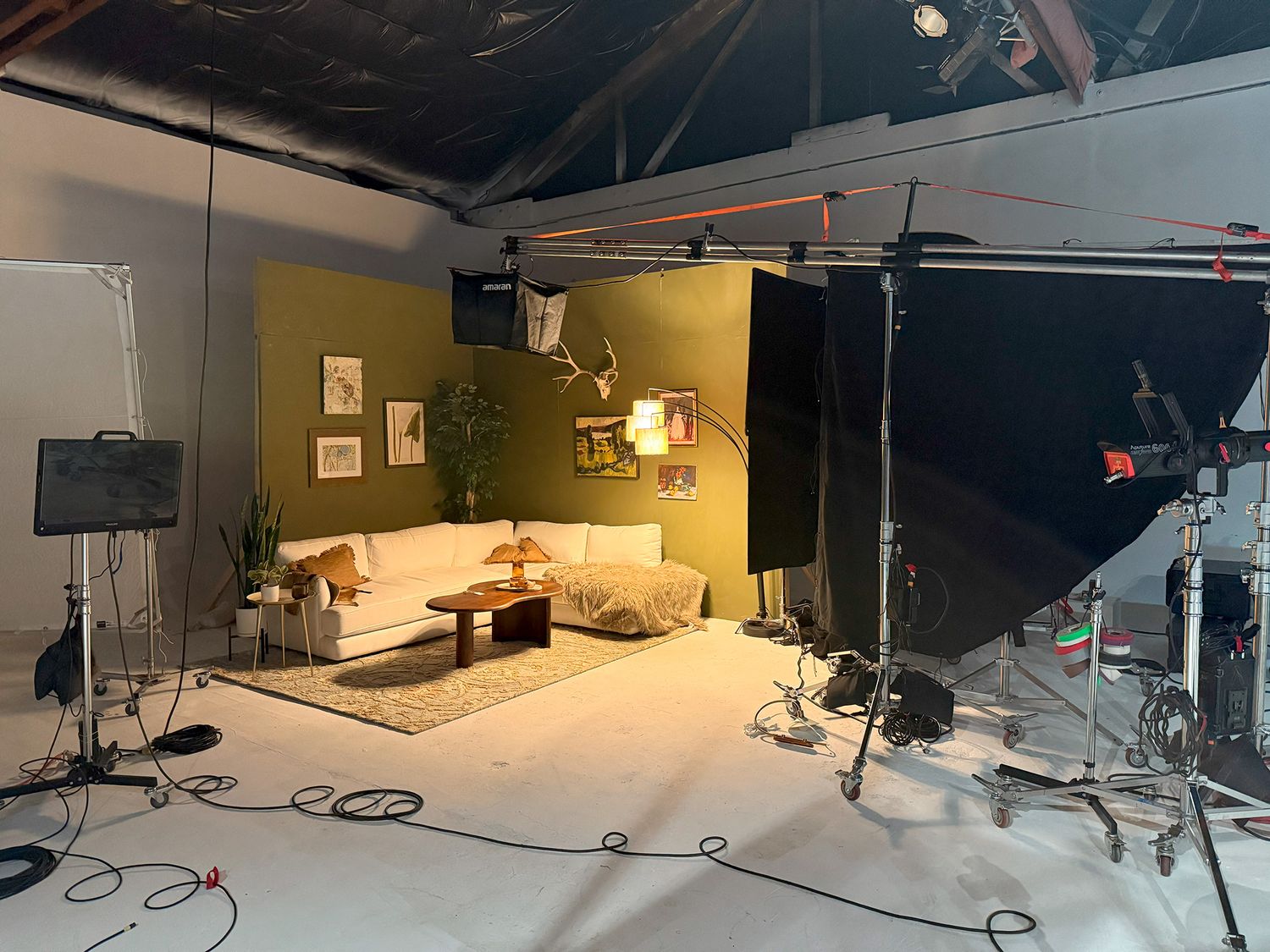 Behind the scenes view of a cozy living room set with professional lighting and film equipment.