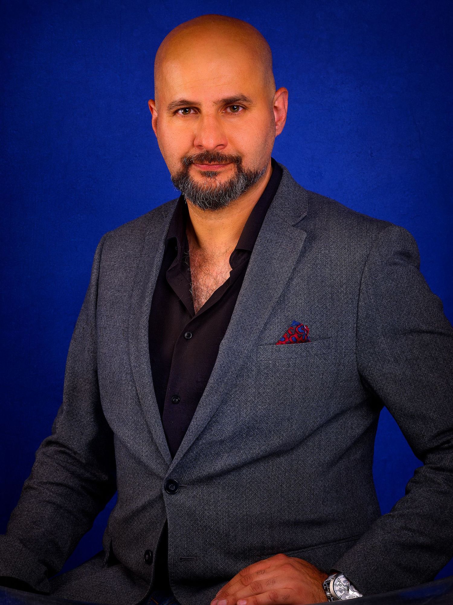 Professional studio portrait against deep blue background in formal business attire.