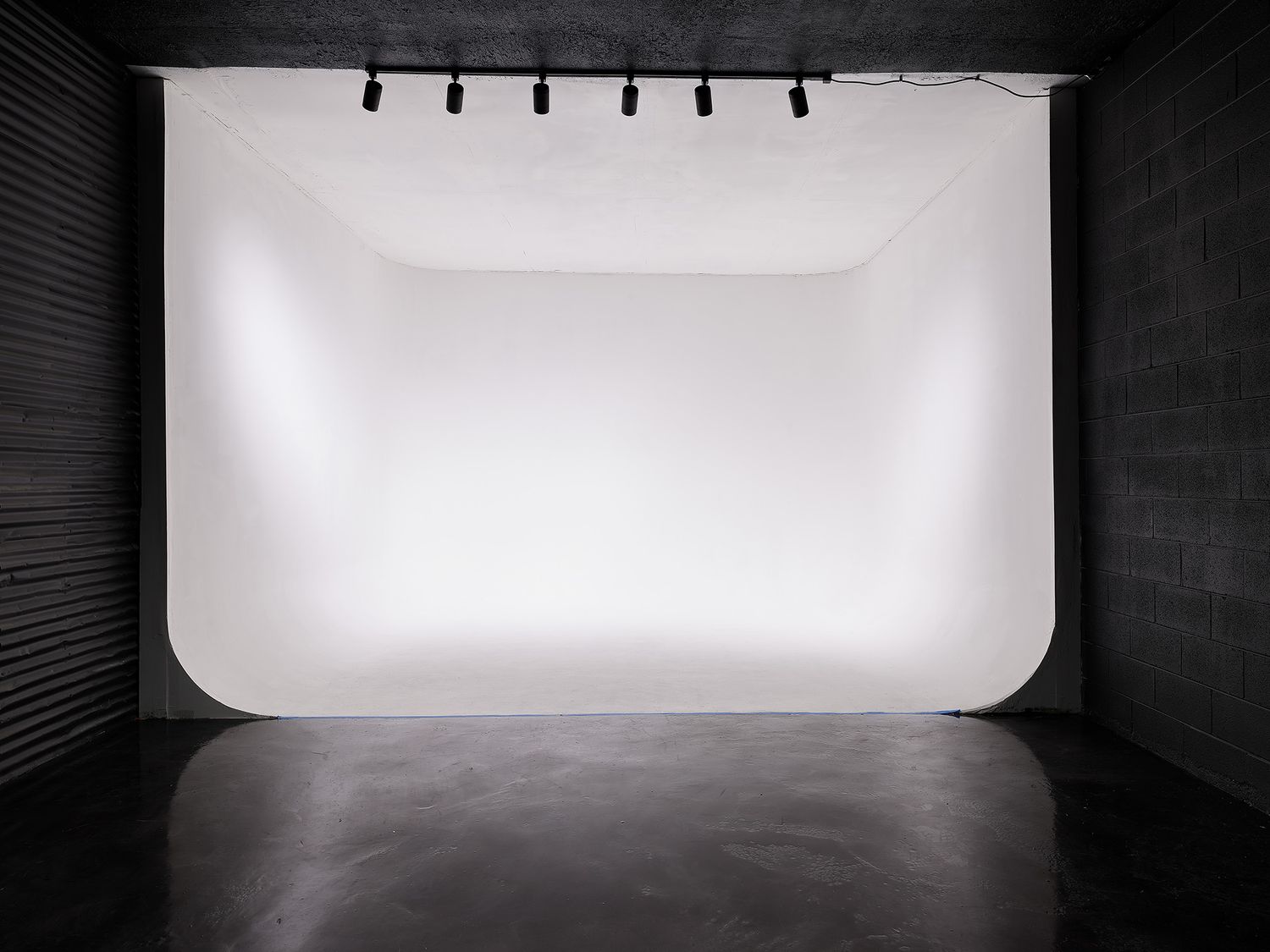 Professional photo studio interior with white cyclorama wall and lighting grid overhead.