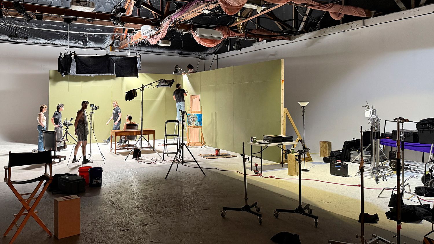 Construction workers renovating an empty commercial office space with exposed ceiling and metal framing.