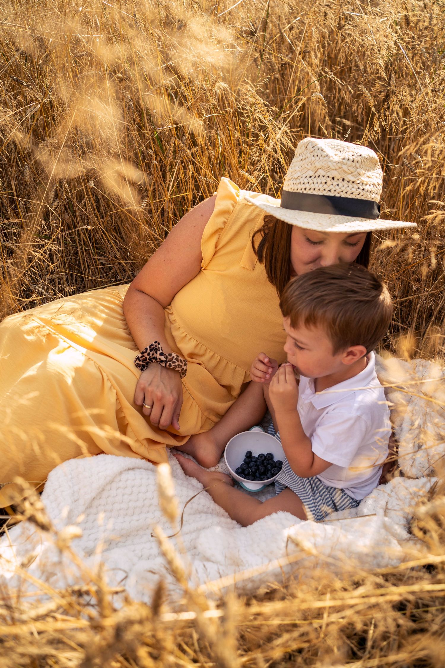 Natürliche Familienfotografie im Freien - liebevolle Momentaufnahme einer Mutter mit Kind beim Picknick im golden Sommerlicht.