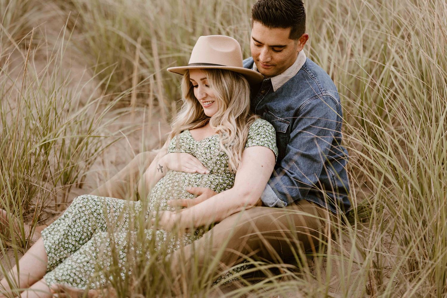 Intimate maternity photos captured in tall grass with natural lighting.