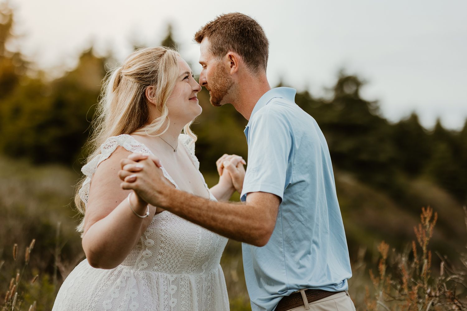 Romantic outdoor photoshoot with warm sunlight filtering through trees in a natural setting.