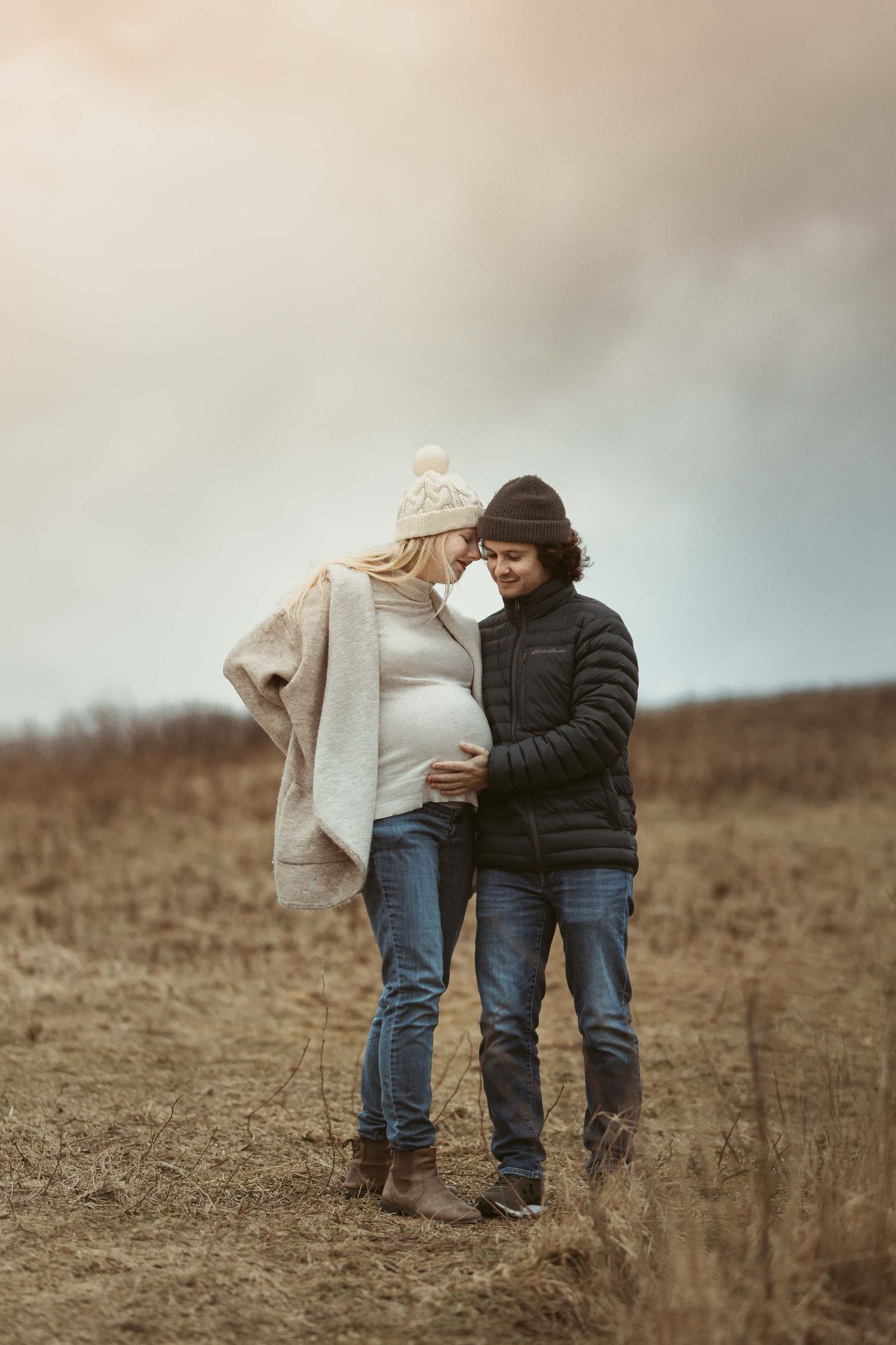 A couple walks together on a brown hill surrounded by mist and fog.