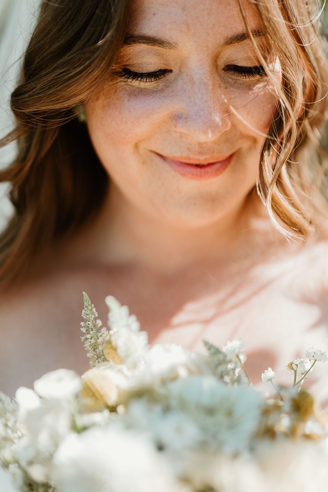 Close-up artistic shots focusing on bride's serene expression with delicate white flowers in foreground.