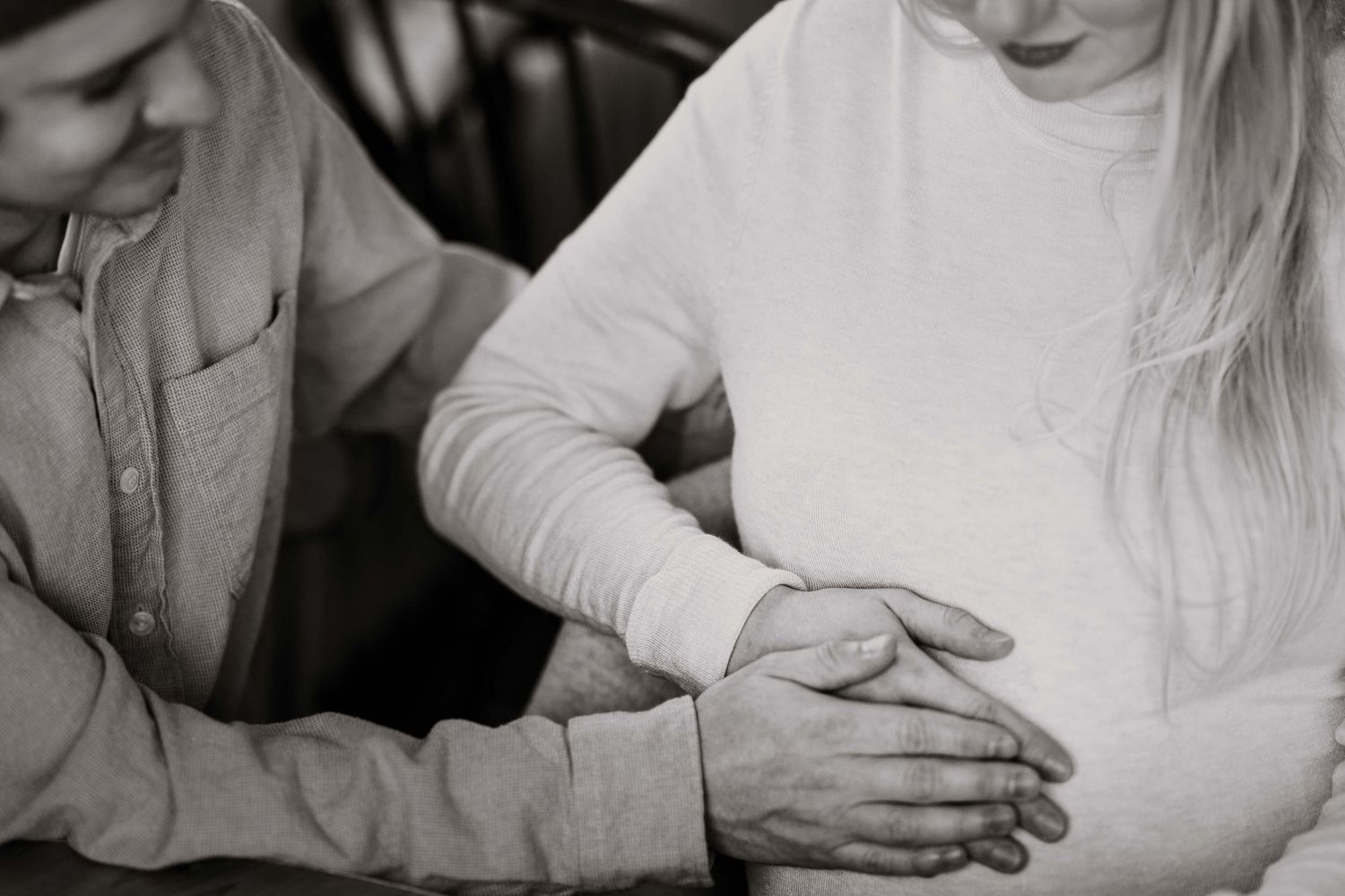 An intimate black and white maternity photo showing gentle moments between expecting parents.