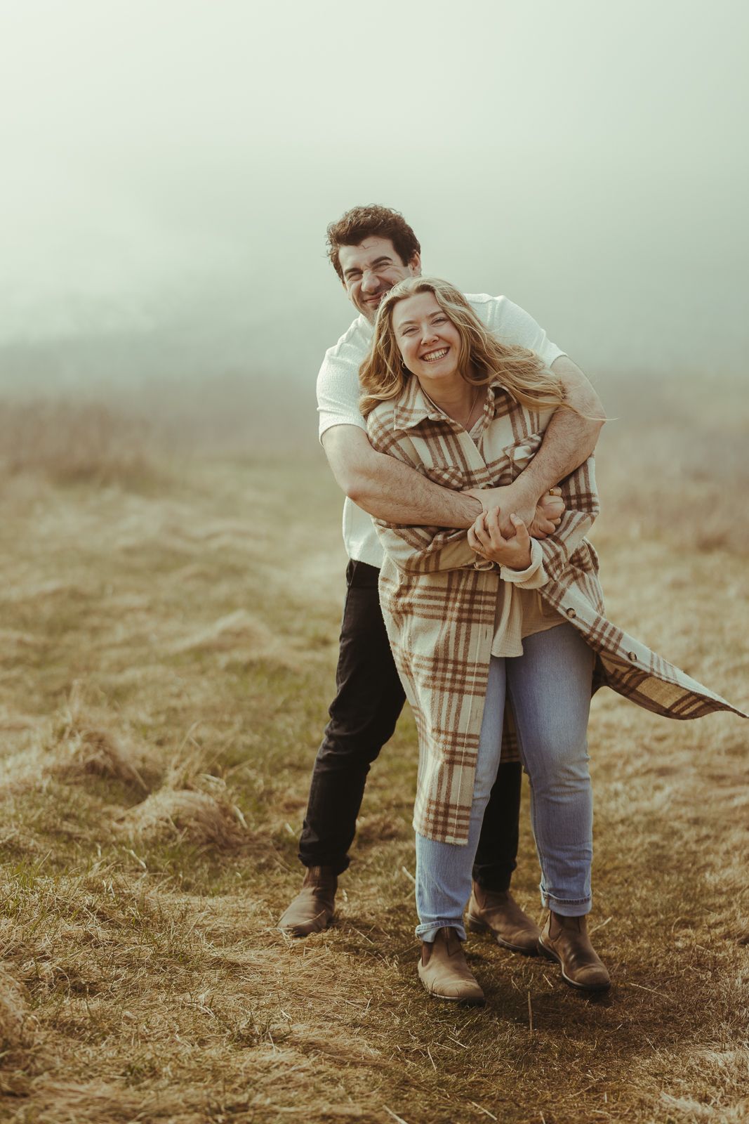 Playful moments captured on a misty hillside in casual autumn attire.