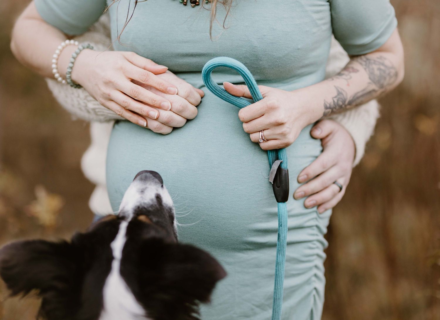 Close up of pregnant belly with hands tenderly placed wearing mint green top.