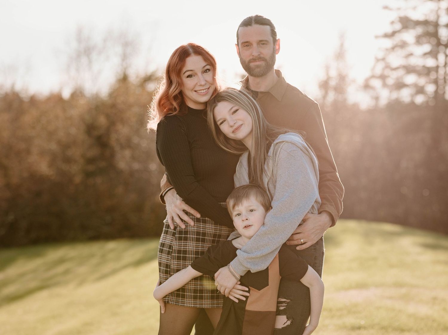 Outdoor family portrait session at sunset with soft golden lighting.