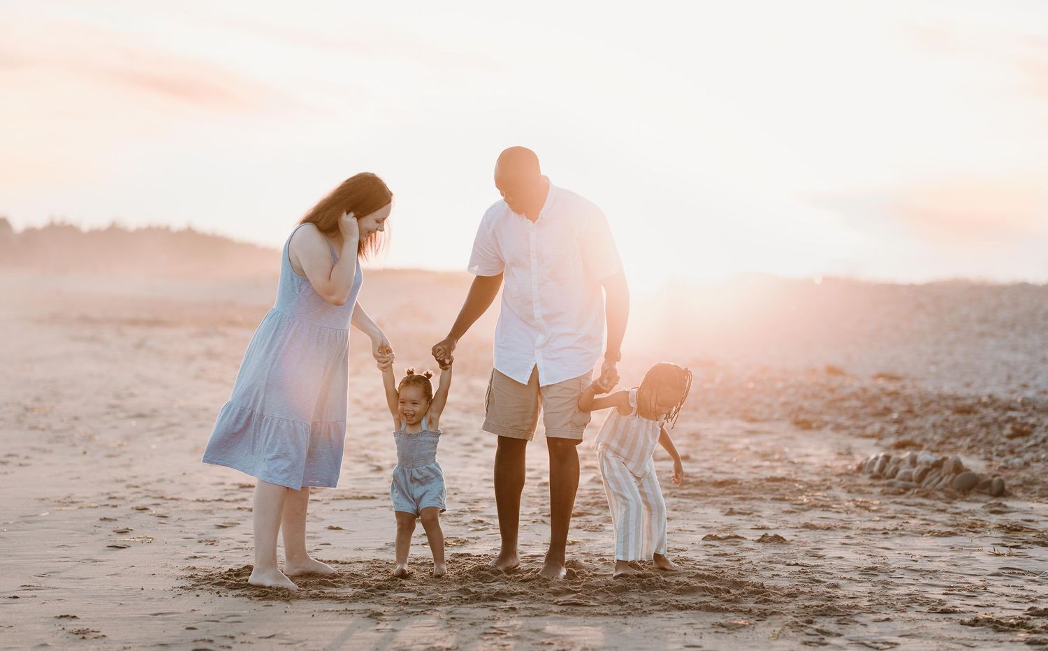 Family walking together along beach shoreline during golden hour sunset.