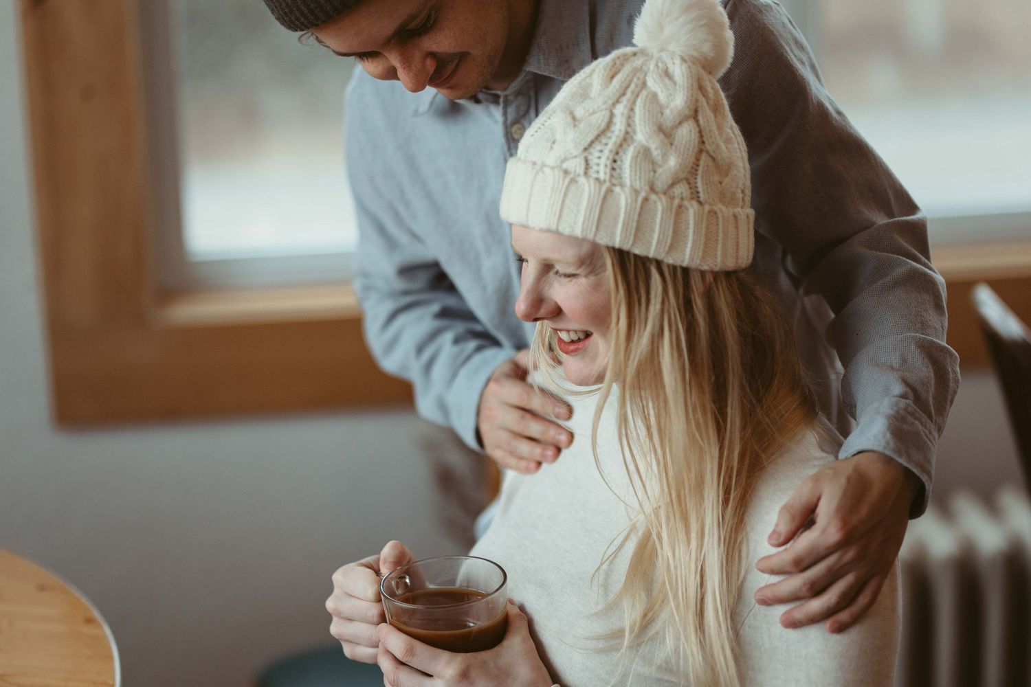 A candid indoor maternity photoshoot showing tender moments between expectant parents.