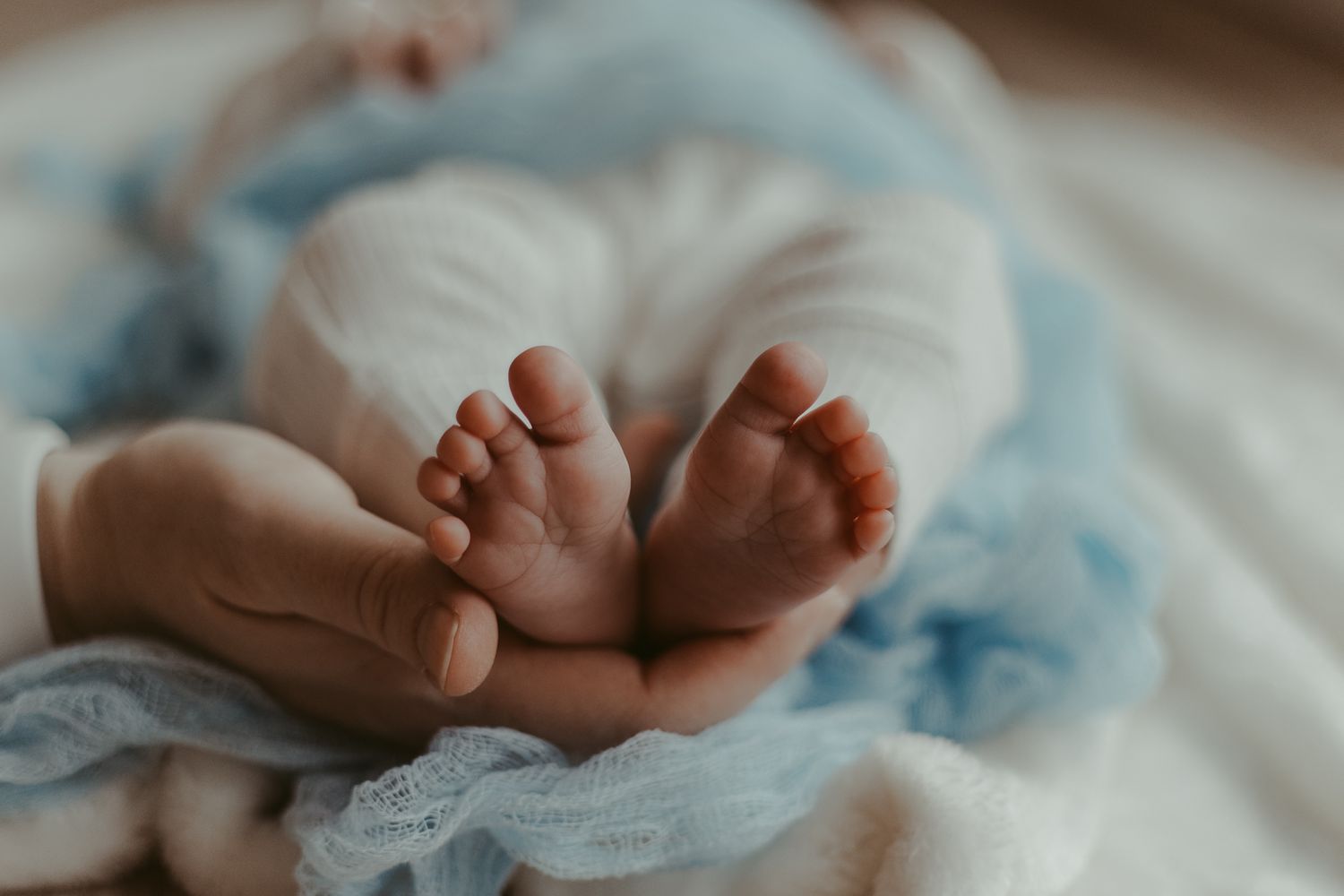 Tiny baby feet resting on a light blue and white blanket.