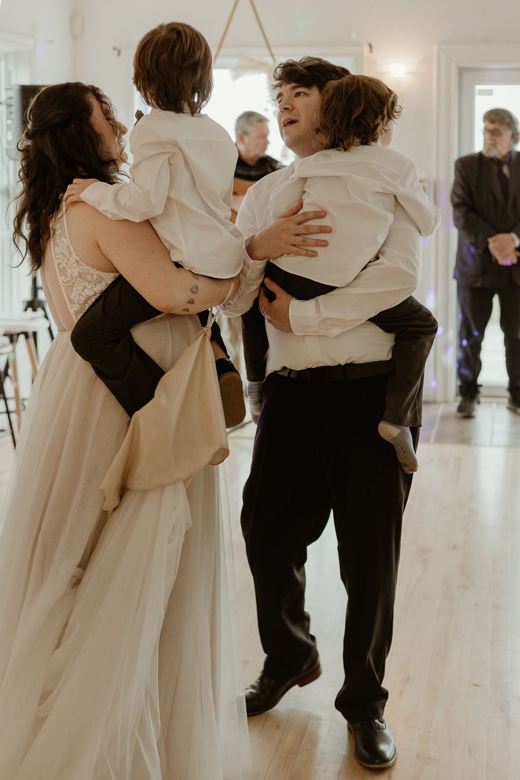 Wedding couples dance in a romantic first dance, with everyone dressed in black and white formal attire.