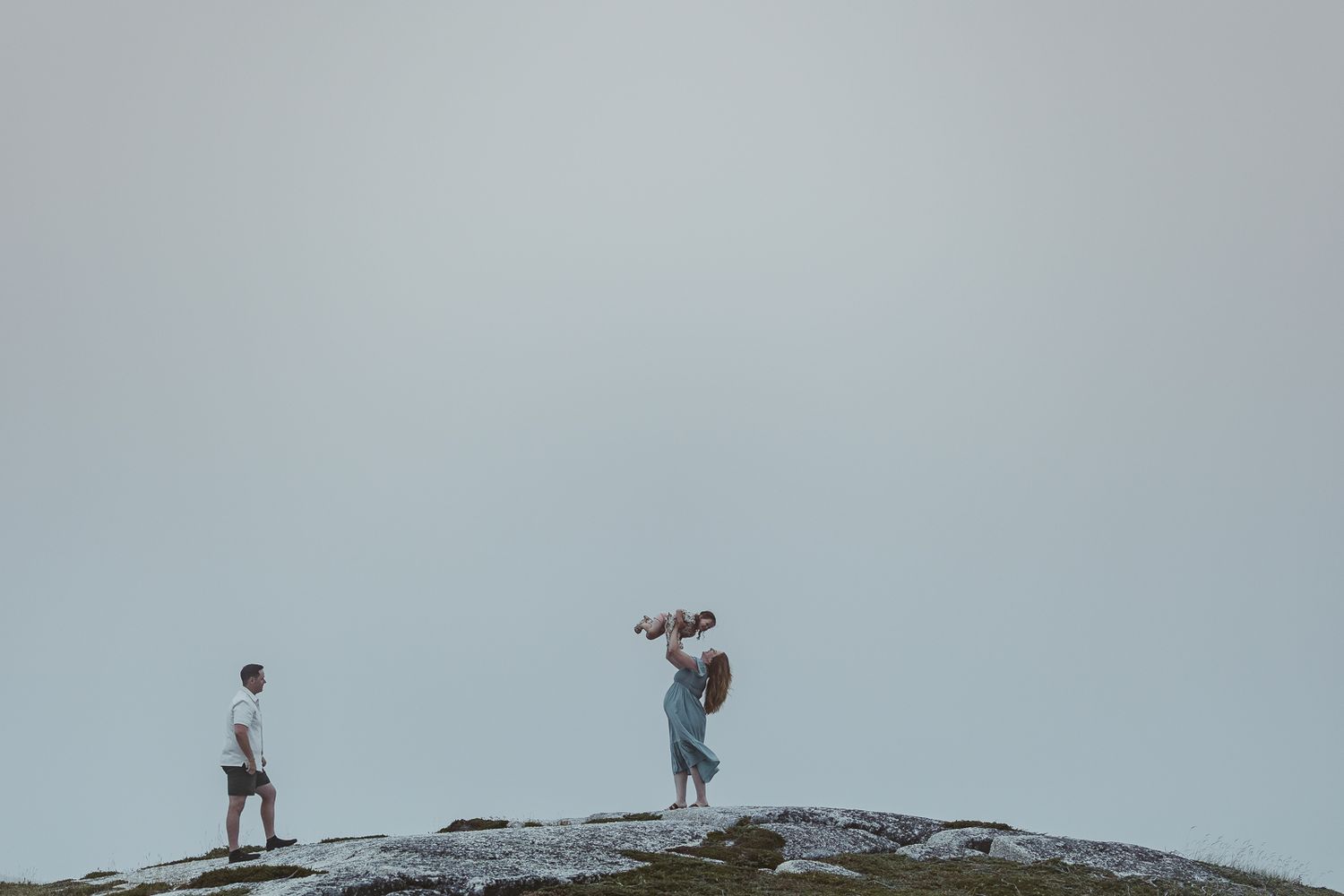 Silhouettes of people walking on a rock formation against cloudy sky.