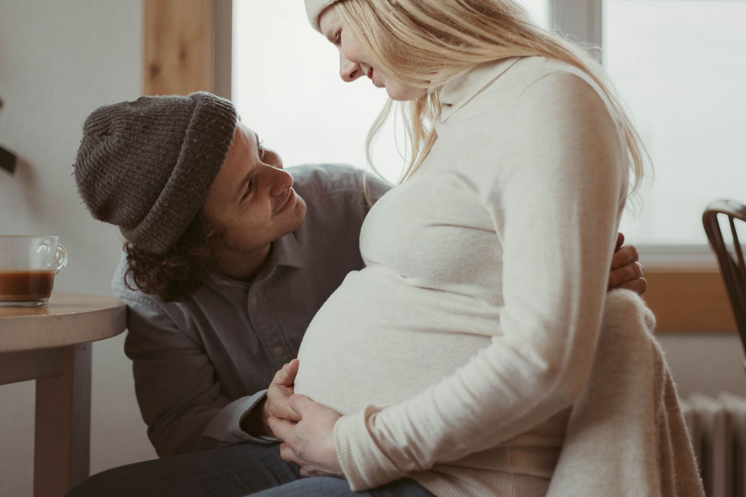 An intimate indoor maternity session captures loving moments between expecting parents.