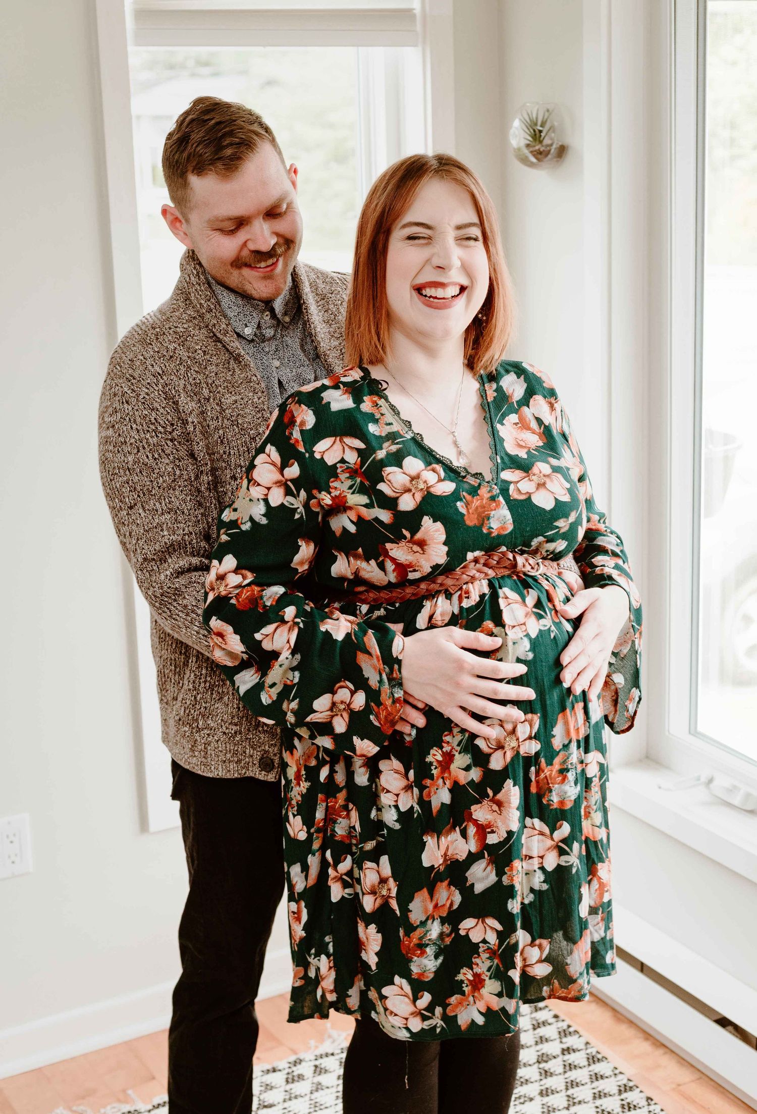 Indoor maternity photos with floral dress and natural window light.