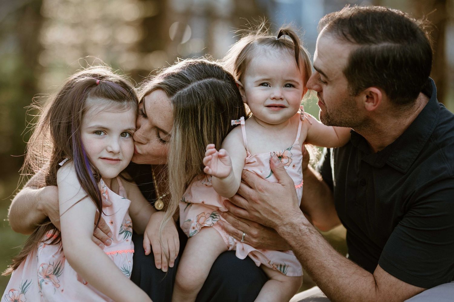 Intimate family moment captured outdoors in warm sunset lighting.